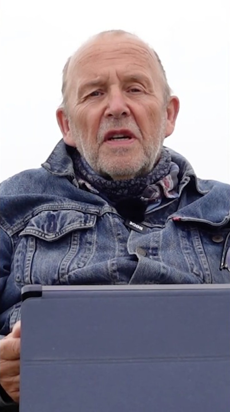 Ralf Alef liest im Freien vor hellem Himmel