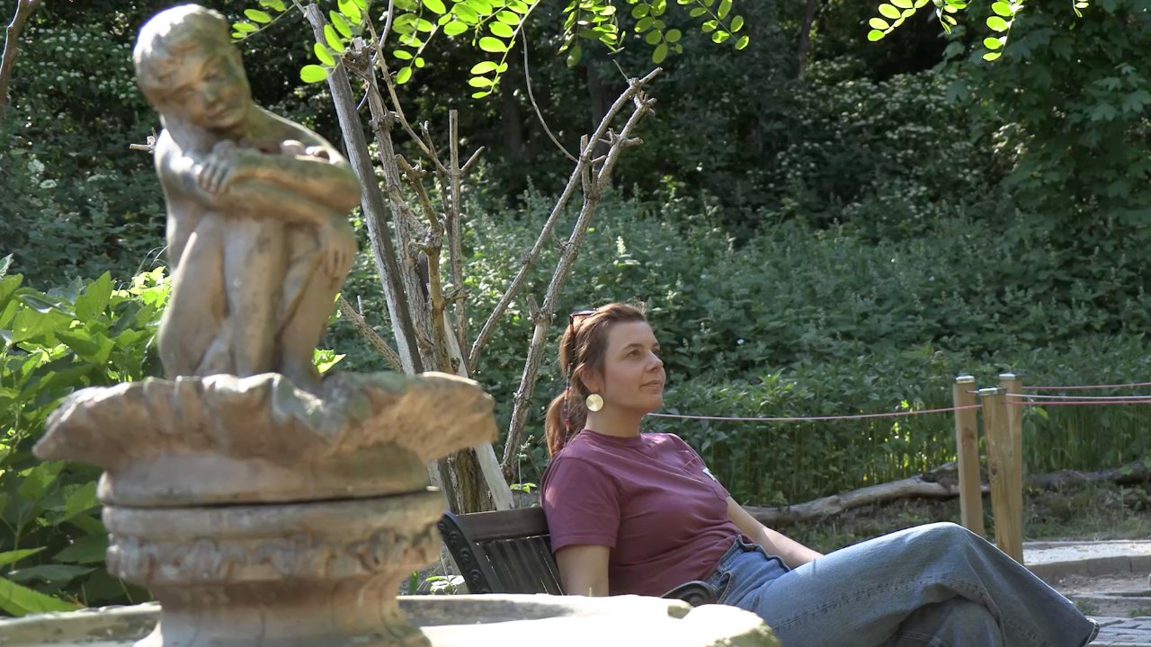 Imagefilm Frau sitzt im Garten neben einem Brunnen